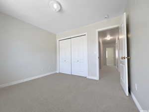 Unfurnished bedroom with light colored carpet and a closet