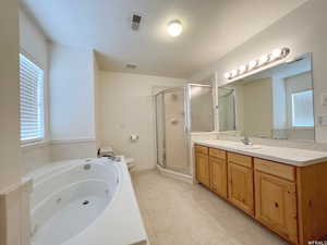 Full bathroom featuring vanity, tile patterned flooring, toilet, and separate shower and tub