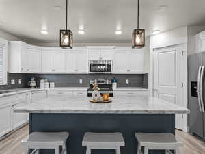 Kitchen featuring white cabinetry, pendant lighting, stainless steel appliances, and a center island