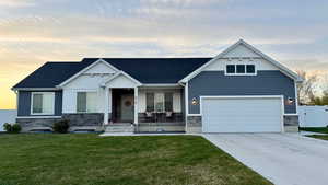 View of front of property featuring driveway, stone siding, board and batten siding, and covered porch
