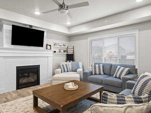 Living room with ceiling fan, hardwood / wood-style floors, and a fireplace