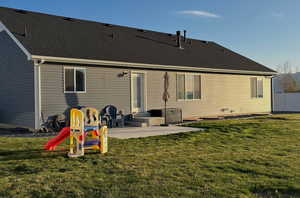 Back of property with a patio area, roof with shingles, and a yard