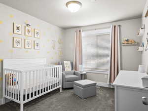 Carpeted bedroom featuring a crib