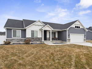 View of front facade featuring a garage, a front yard, and covered porch