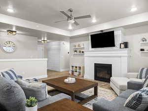 Living room with ceiling fan, a fireplace, and light hardwood / wood-style flooring