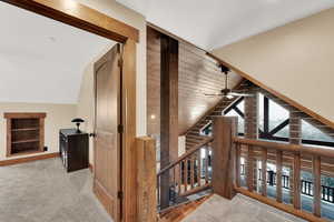 Hallway with light carpet and vaulted ceiling