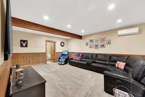 Carpeted living room featuring beamed ceiling, a wall mounted AC, and wooden walls