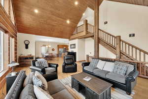 Living room with high vaulted ceiling, light wood-type flooring, an inviting chandelier, and wood ceiling