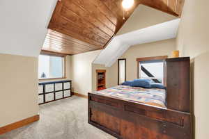 Carpeted bedroom featuring vaulted ceiling and wooden ceiling