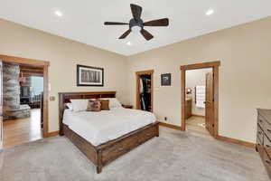 Carpeted bedroom with ceiling fan, a spacious closet, ensuite bath, and a closet