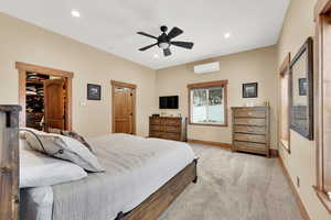 Carpeted bedroom with an AC wall unit and ceiling fan