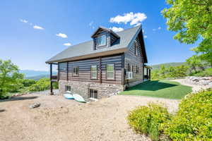 View of side of home with a lawn, a mountain view, and a shingled roof