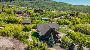 Aerial view of property and surrounding area with a mountainous background and a heavily wooded area
