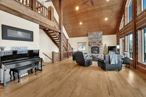 Living room featuring a high ceiling, a stone fireplace, and light hardwood / wood-style flooring