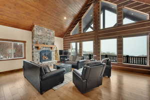 Living room featuring high vaulted ceiling, a fireplace, light hardwood / wood-style floors, and wooden ceiling