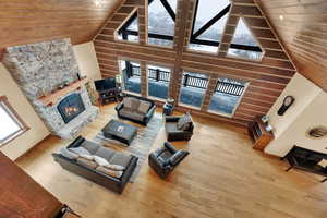 Living room with hardwood / wood-style floors, a stone fireplace, wooden ceiling, and a healthy amount of sunlight