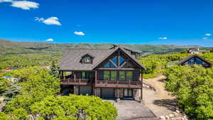 Log home featuring an attached garage, asphalt driveway, stone siding, and a mountain view