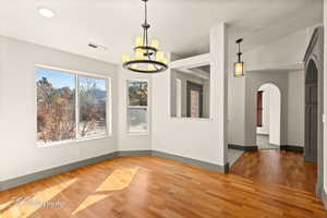 Unfurnished dining area featuring hardwood / wood-style flooring, a textured ceiling, and an inviting chandelier