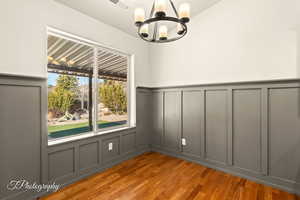 Empty room with hardwood / wood-style flooring and an inviting chandelier