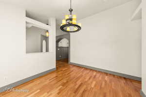 Unfurnished dining area featuring hardwood / wood-style flooring and an inviting chandelier