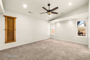 Empty room with carpet floors, vaulted ceiling, and ceiling fan