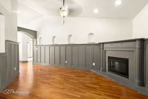 Unfurnished living room with vaulted ceiling, ceiling fan, a fireplace, and light wood-type flooring