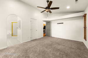 Unfurnished bedroom with ceiling fan, ensuite bath, vaulted ceiling, and carpet