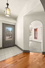 Foyer with vaulted ceiling, light hardwood / wood-style floors, and a textured ceiling