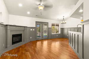 Unfurnished living room with french doors, lofted ceiling, light hardwood / wood-style flooring, a textured ceiling, and ceiling fan with notable chandelier