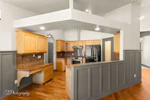 Kitchen featuring gas stove, tasteful backsplash, black refrigerator, dark stone counters, and light hardwood / wood-style floors