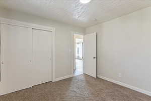 Unfurnished bedroom featuring carpet, a textured ceiling, and a closet