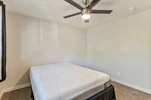 Carpeted bedroom with a textured ceiling and ceiling fan