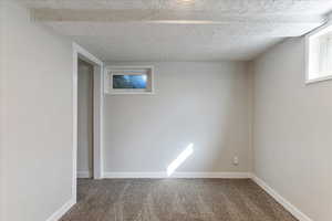 Basement with a textured ceiling and dark colored carpet