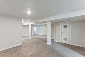 Basement with carpet flooring and a textured ceiling