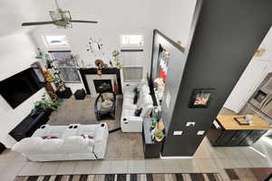 Living room featuring high vaulted ceiling, ceiling fan, and light tile patterned flooring