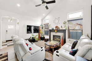 Living room with ceiling fan, plenty of natural light, a fireplace, and high vaulted ceiling