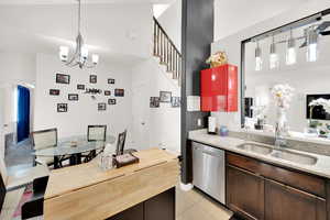 Kitchen with dark brown cabinetry, sink, light stone counters, light tile patterned floors, and dishwasher