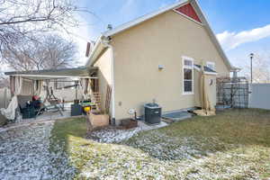 Rear view of house with a patio, central AC unit, and a lawn