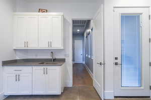 Bar featuring sink and white cabinets