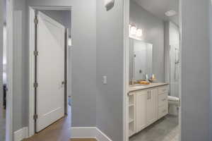 Bathroom featuring hardwood / wood-style flooring, vanity, toilet, and a shower