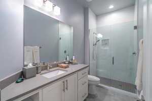 Bathroom featuring vanity, toilet, an enclosed shower, and tile patterned flooring