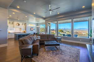 Living room featuring a mountain view, dark wood-type flooring, ceiling fan with notable chandelier, and sink