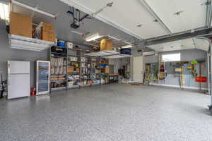 Garage featuring white refrigerator and a garage door opener