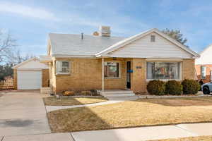 View of front facade featuring a garage, an outdoor structure, and a front lawn