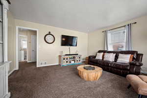 Living room featuring a textured ceiling and dark carpet