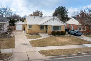 View of front of house featuring a garage, an outdoor structure, and a front yard