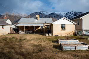 Back of house featuring a wall mounted AC, a mountain view, and a lawn