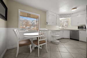 Kitchen with white cabinetry, light tile patterned floors, sink, and appliances with stainless steel finishes