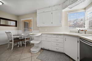 Kitchen featuring white cabinets, light tile patterned floors, sink, and dishwasher