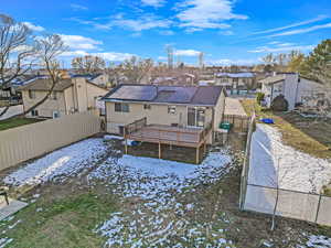 Snow covered house featuring a deck and solar panels